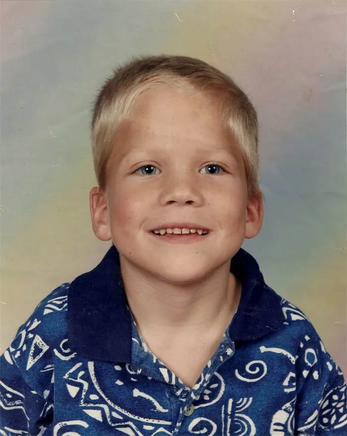 School portrait of Jimmy as a young boy with blond hair and a blue patterned shirt.